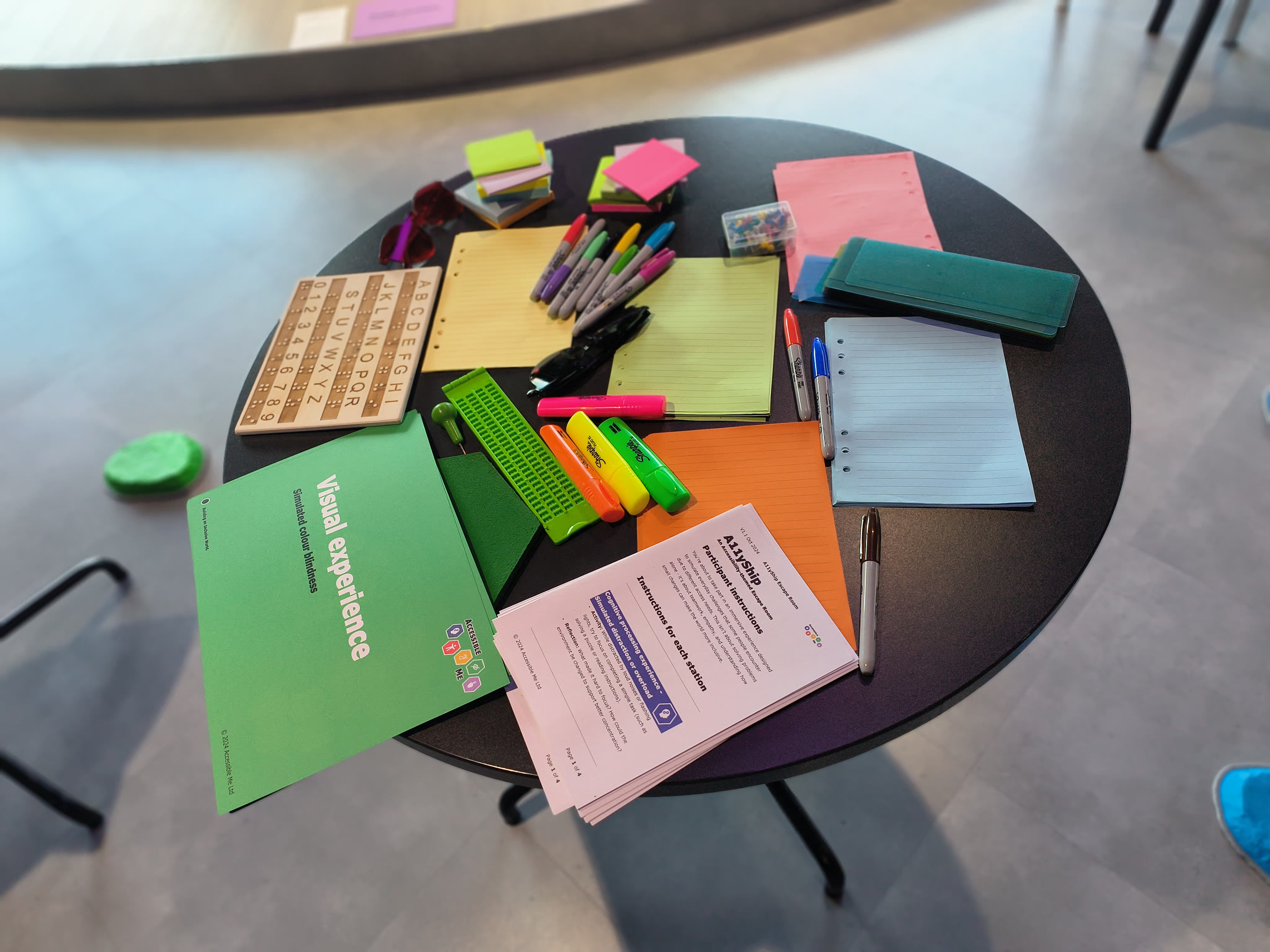 A table with different coloured paper and  pens, and coloured glasses that cause colours to seemingly disappear